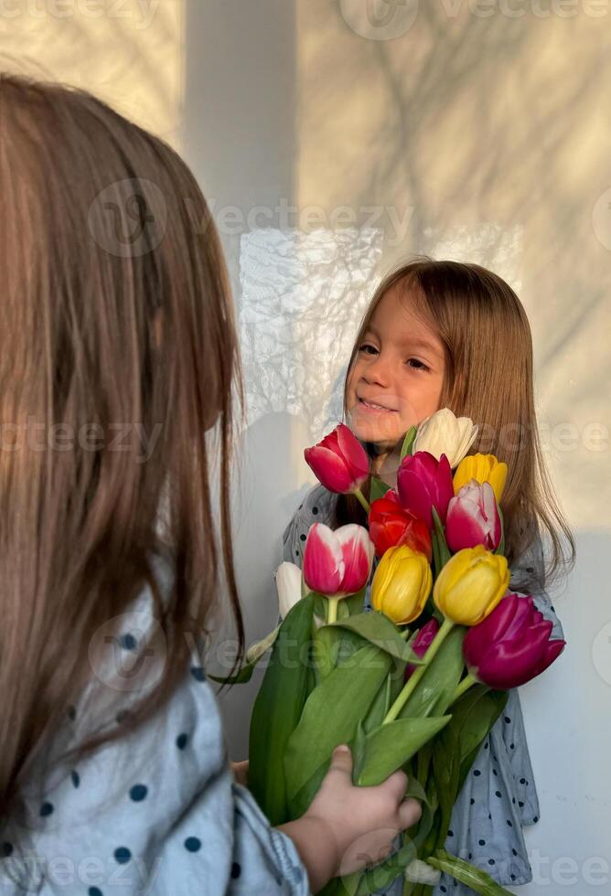 Siblings or twin day. Women's or Mother's Day. Portrait of two smiling little girl with a bouquet of tulips. Space for text. photo