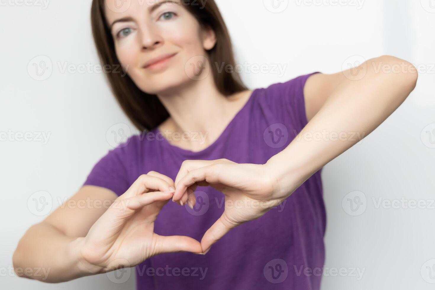 Inspire inclusion. Woman holding her hands in the shape of a heart and holding them in front of her, dressed purple t-shirt. International women's day concept. photo