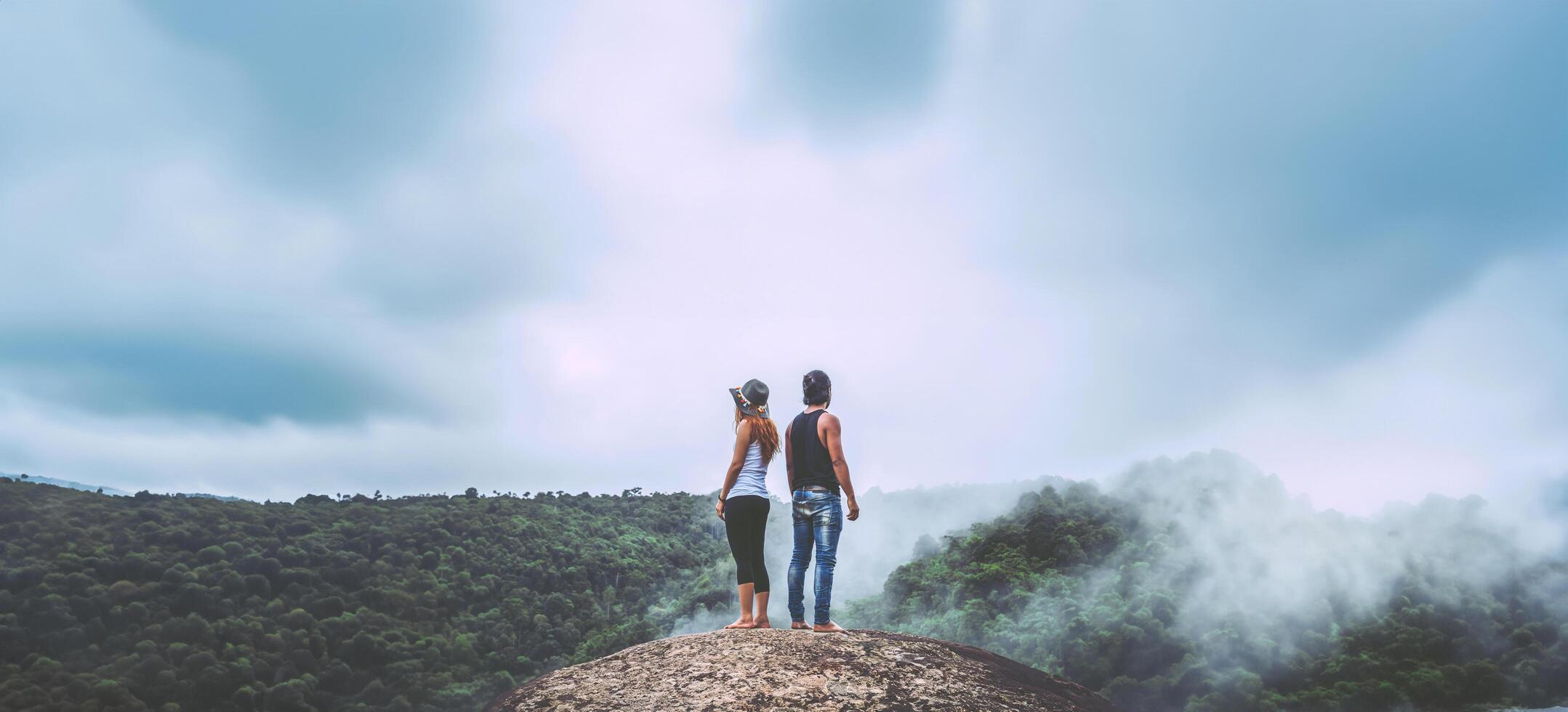 Lover women and men asians travel relax in the holiday. Standing hugged on a rocky cliff. Wild nature wood on the mountain. photo