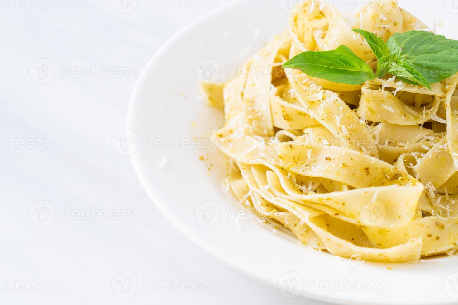 pasta fettuccine al pesto con queso parmesano encima foto