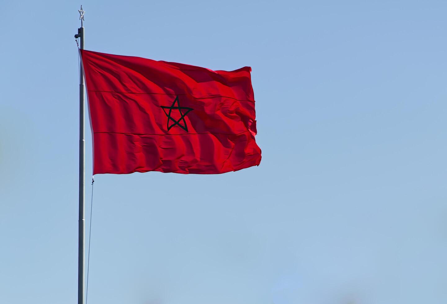 The flag of Morocco fluttering on blue sky background photo