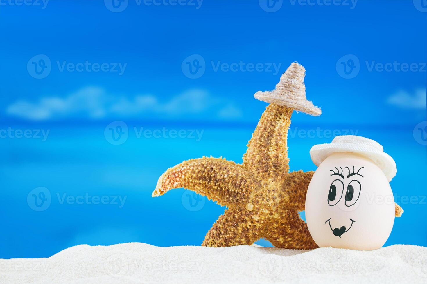 White egg with smile hugs starfish on sea . Easter in hot countries. Copy space photo