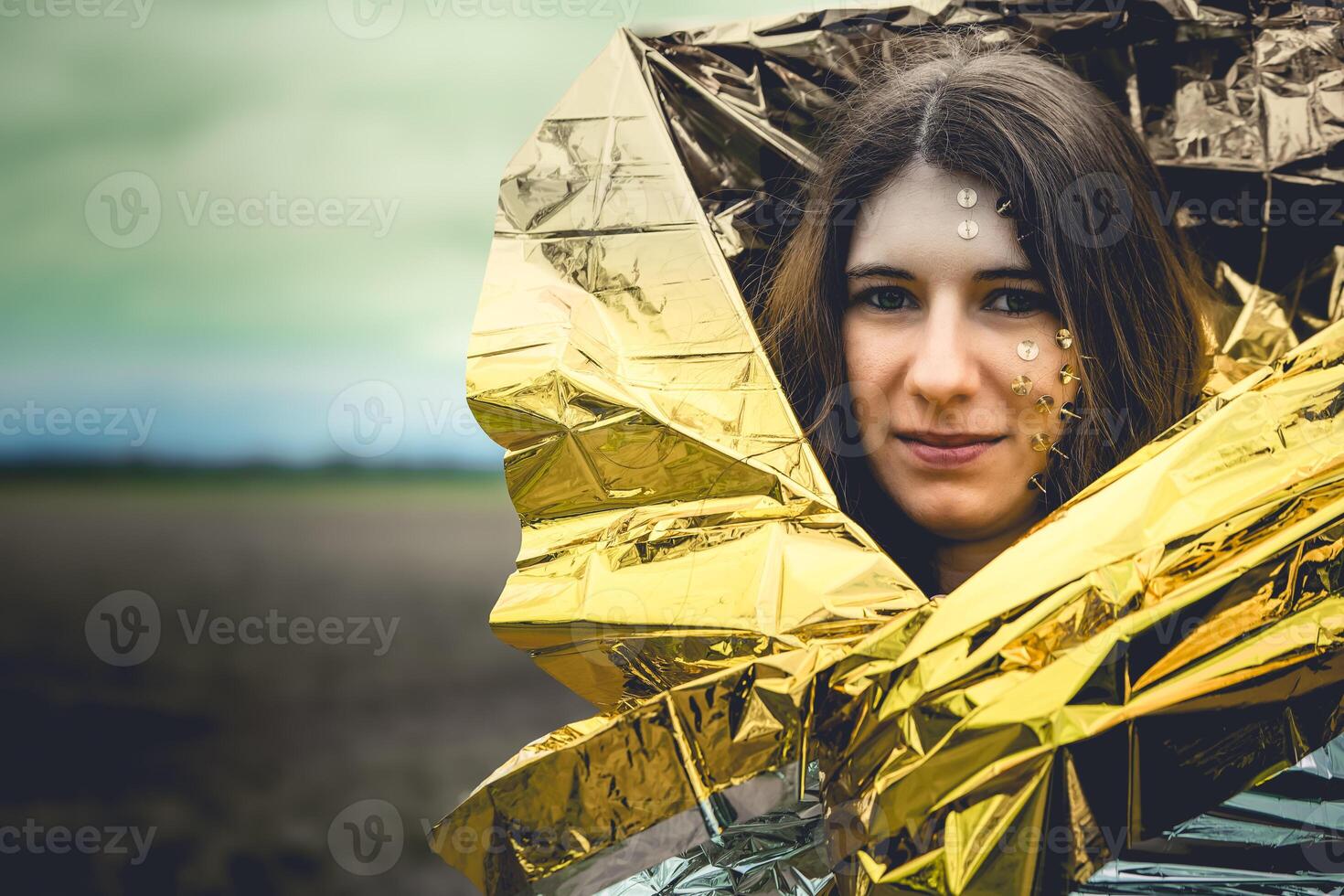 woman as a fantasy representation with tacks in her face and a golden rescue blanket photo