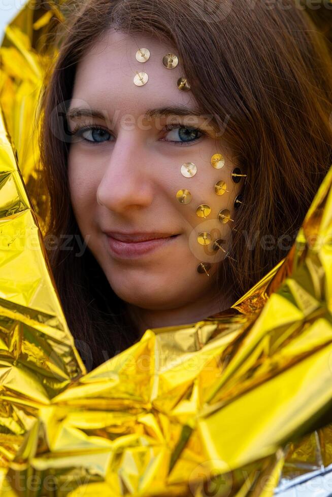 woman as a fantasy representation with tacks in her face and a golden rescue blanket photo