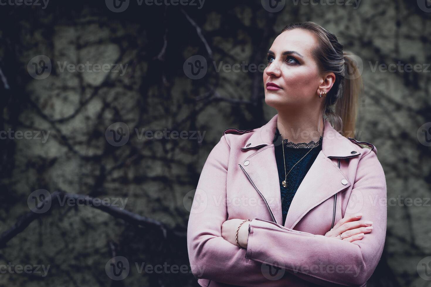 mujer en un rosado chaqueta es en pie en frente de un pared foto