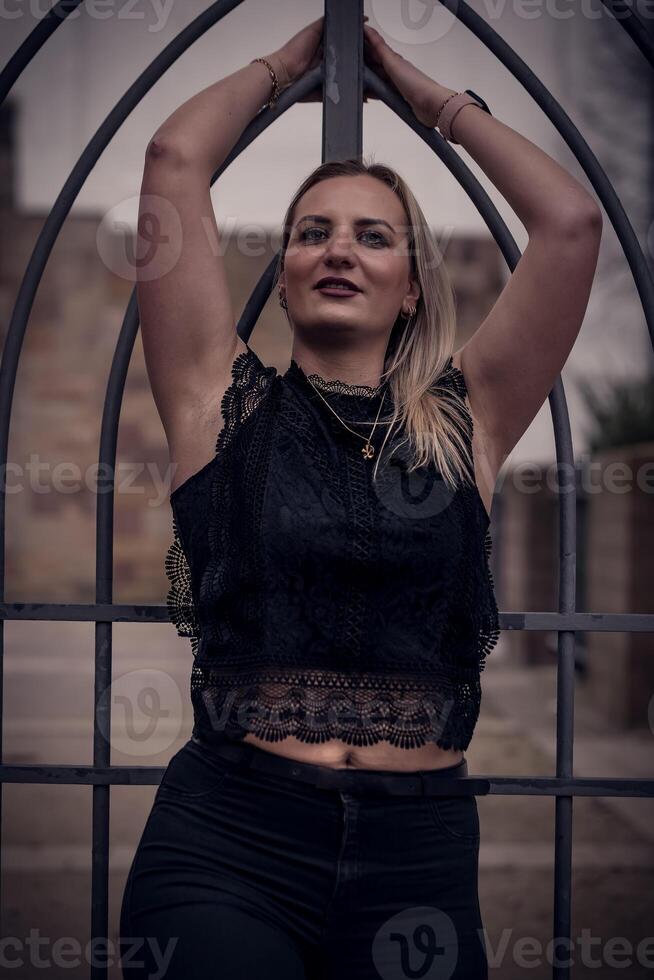 a pretty woman poses in front of a black grid in the city photo