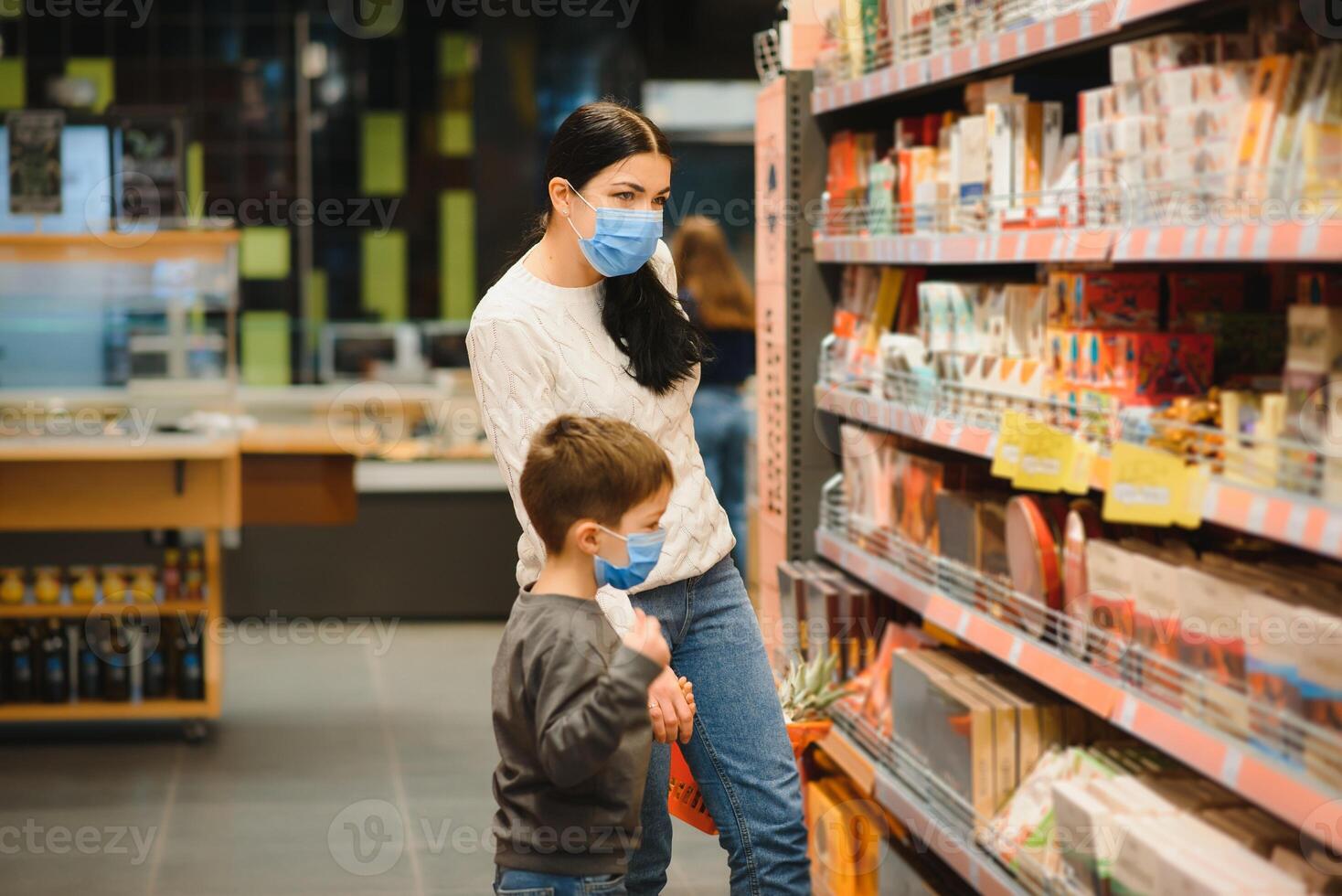 joven mujer y su niño vistiendo protector cara mascaras tienda un comida a un supermercado durante el coronavirus epidemia o gripe brote. foto