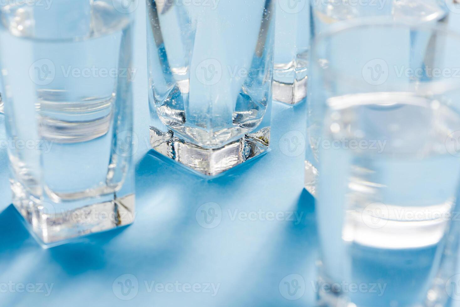 Line of glasses, a glass with water, on a light blue background. Difference concept. Equality concept. photo