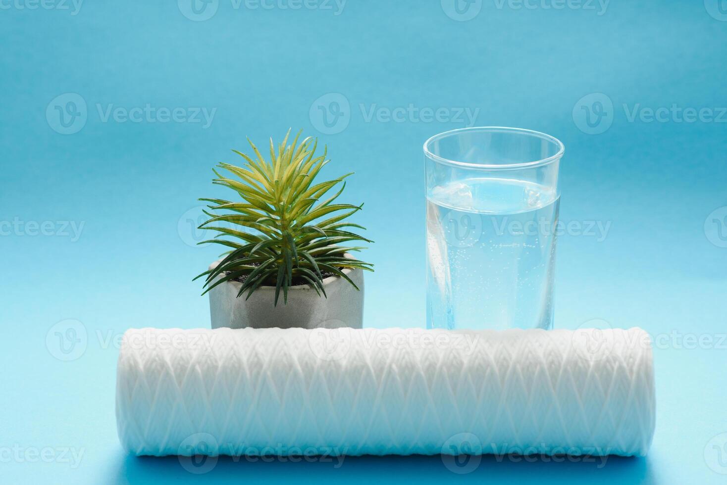 Glasses of dirty and clear water and filter cartridges to domestic water treatment systems at bright blue background. Concept of water treatment. photo