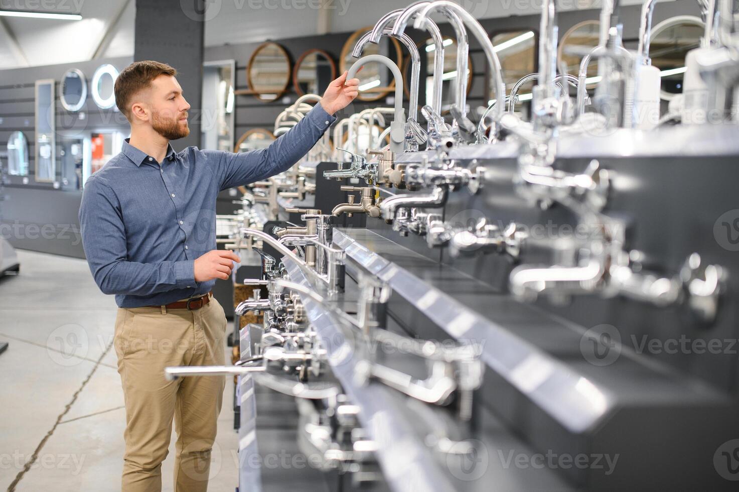A large selection of water faucets. Man chooses a products in a sanitary ware store photo