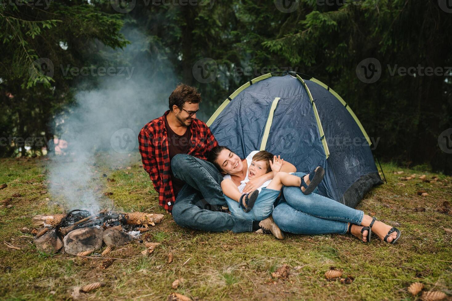 Family near the fire in the forest. Parent with child on a tent background. National Park. Hike with children. Active summer holidays. photo