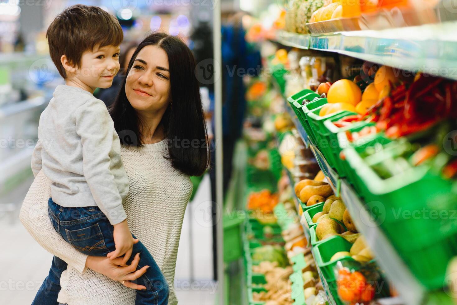 woman and child boy during family shopping with trolley at supermarket photo