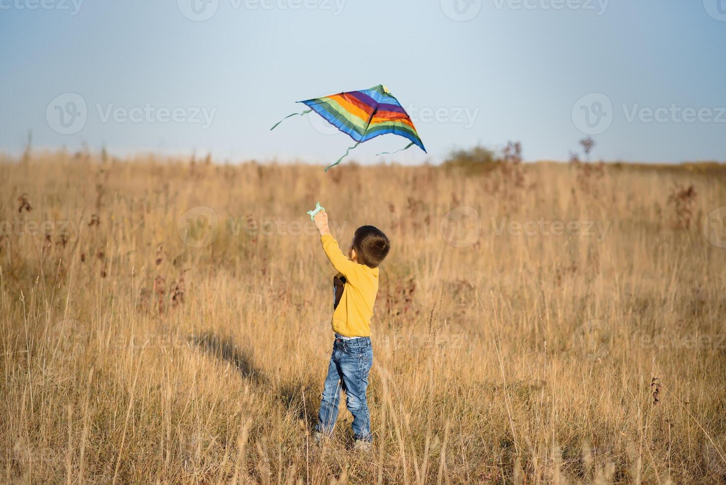 Little boy with kite flying over his head photo