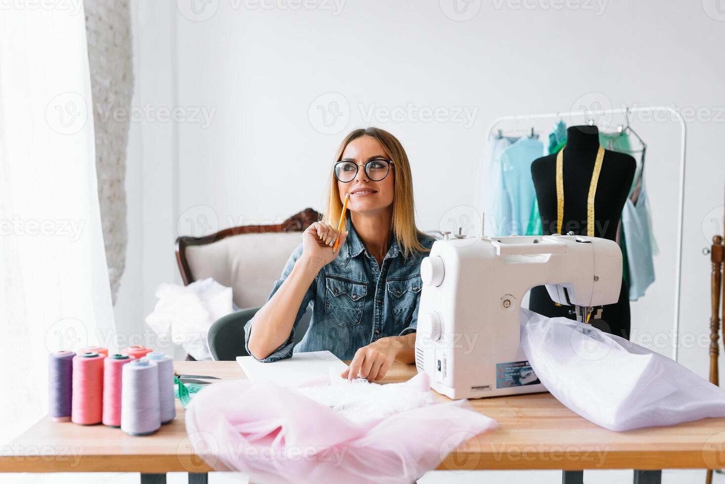 atractivo hembra Moda diseñador es trabajando en su taller. elegante mujer en proceso de creando nuevo ropa colección foto