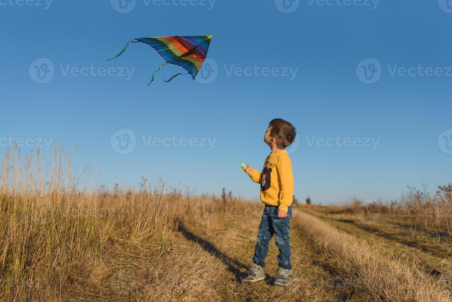 Little boy with kite flying over his head photo