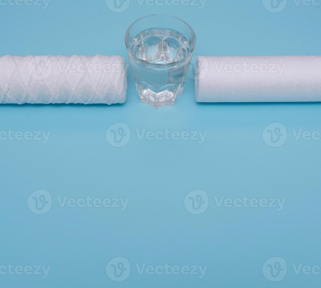 Water filters. Carbon cartridges and a glass on a blue background. Household filtration system. photo