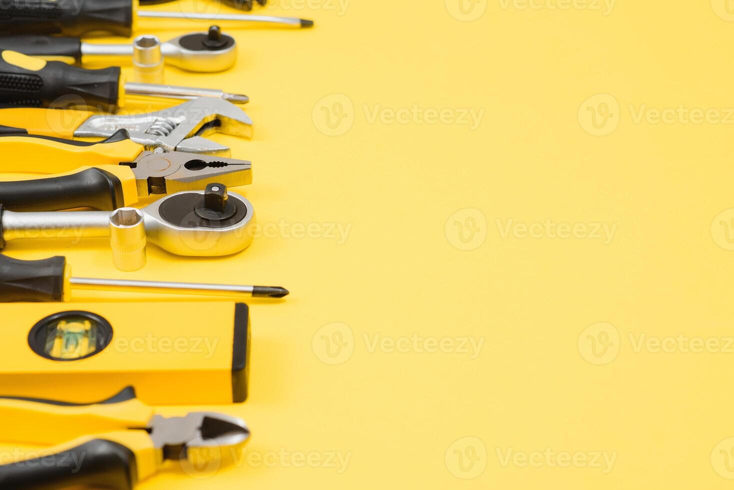 Yellow and black handy tools pilers and screwdriver isolated on yellow background. photo