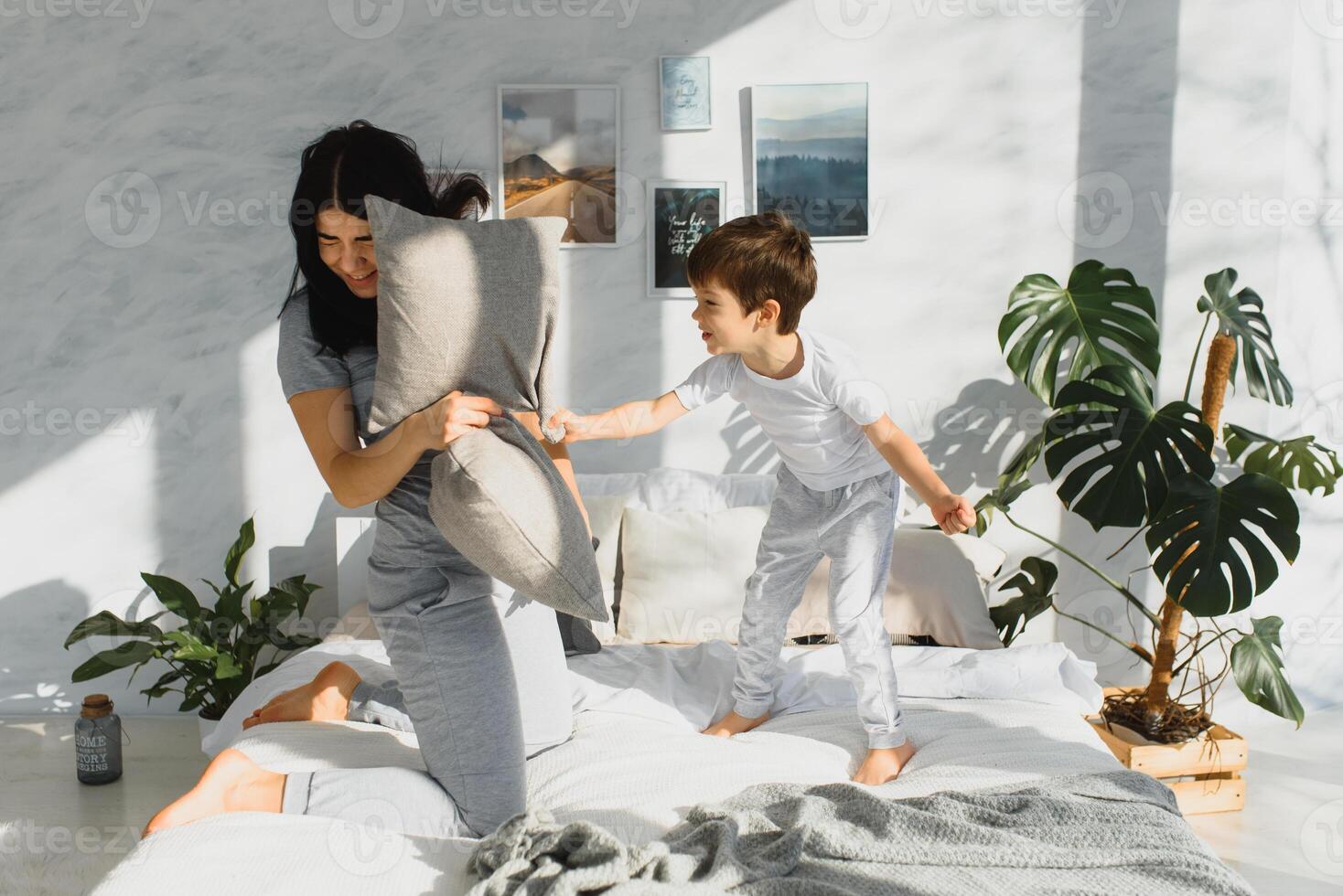 contento madre y hijo luchando con almohadas en cama en fin de semana Mañana foto