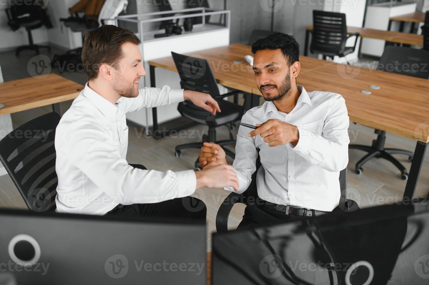 Two successful trader sitting in office and looking at screen, checking cryptocurrency information data on finance market graph, pointing on monitor photo