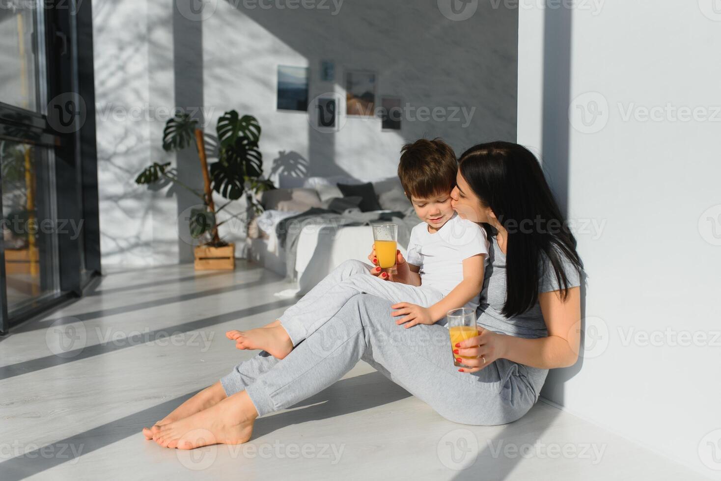 joven madre con su 4 4 años antiguo pequeño hijo vestido en pijama son relajante y jugando en el dormitorio a el fin de semana juntos, perezoso Mañana. foto