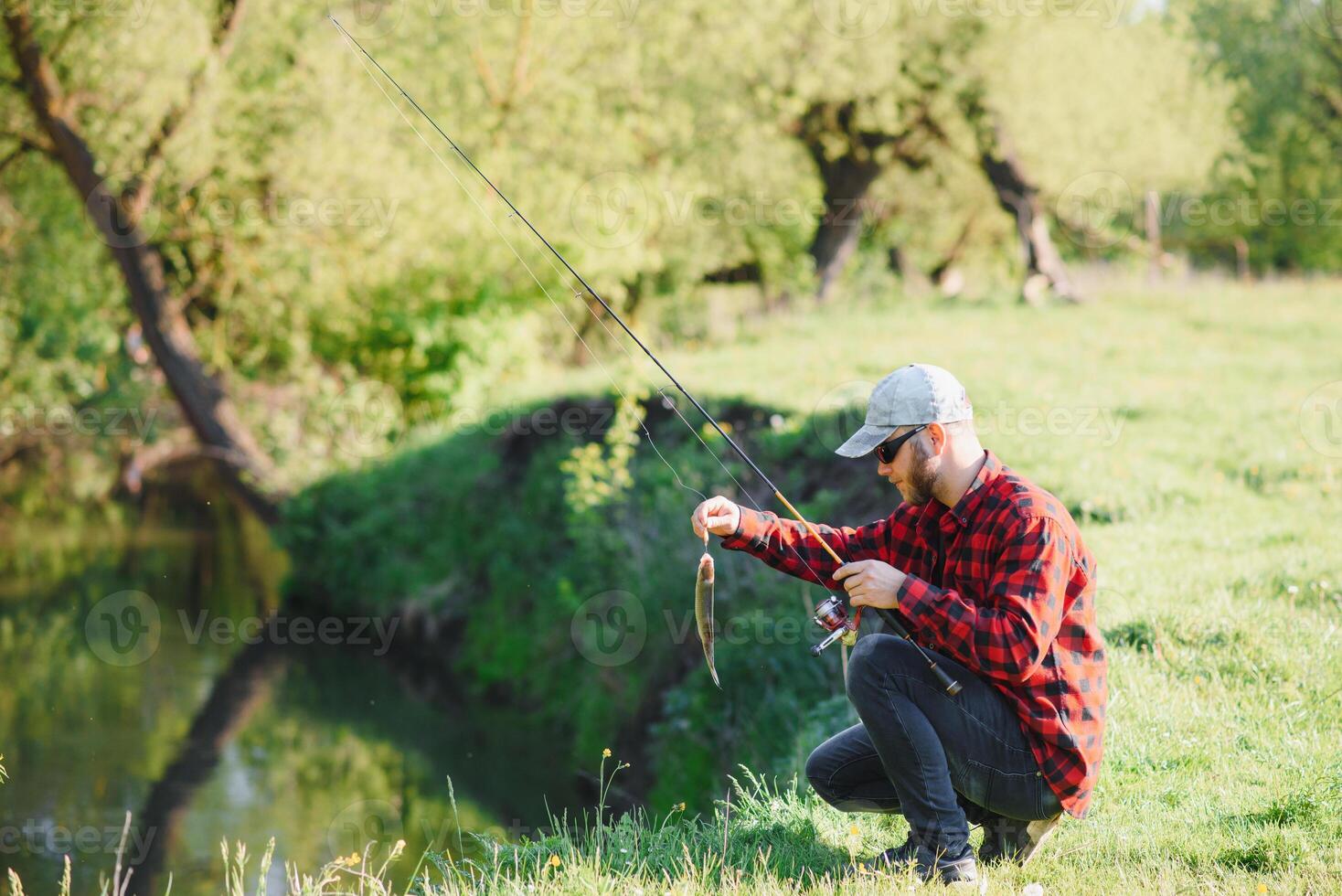 young fisherman fishes near the river. The concept of outdoor activities and fishing photo