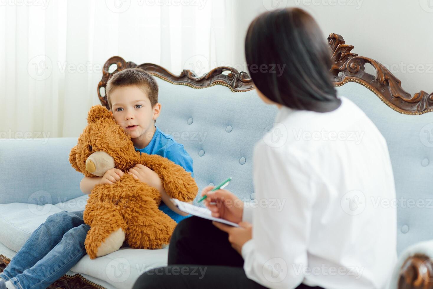 Young female psychologist working with little boy in office photo