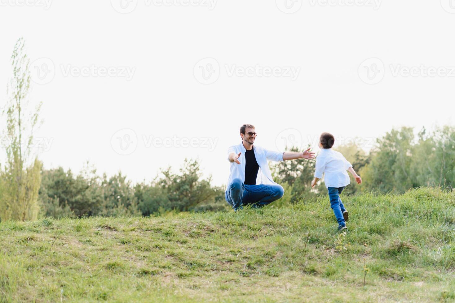 Handsome dad with his little cute son are having fun and playing on green grassy lawn. Happy family concept. Beauty nature scene with family outdoor lifestyle. family resting together. Fathers day photo