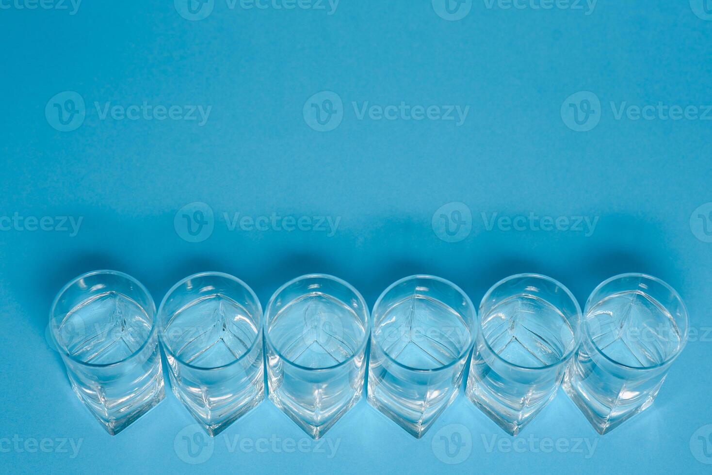 Line of glasses, a glass with water, on a light blue background. Difference concept. Equality concept. photo