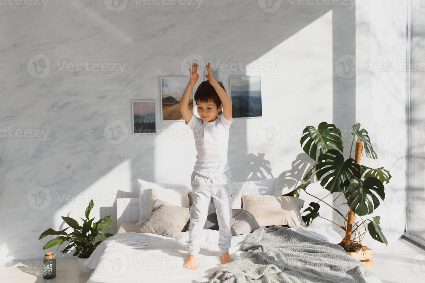 Happy kid in pajama jumping on the bed and having fun in the morning. photo