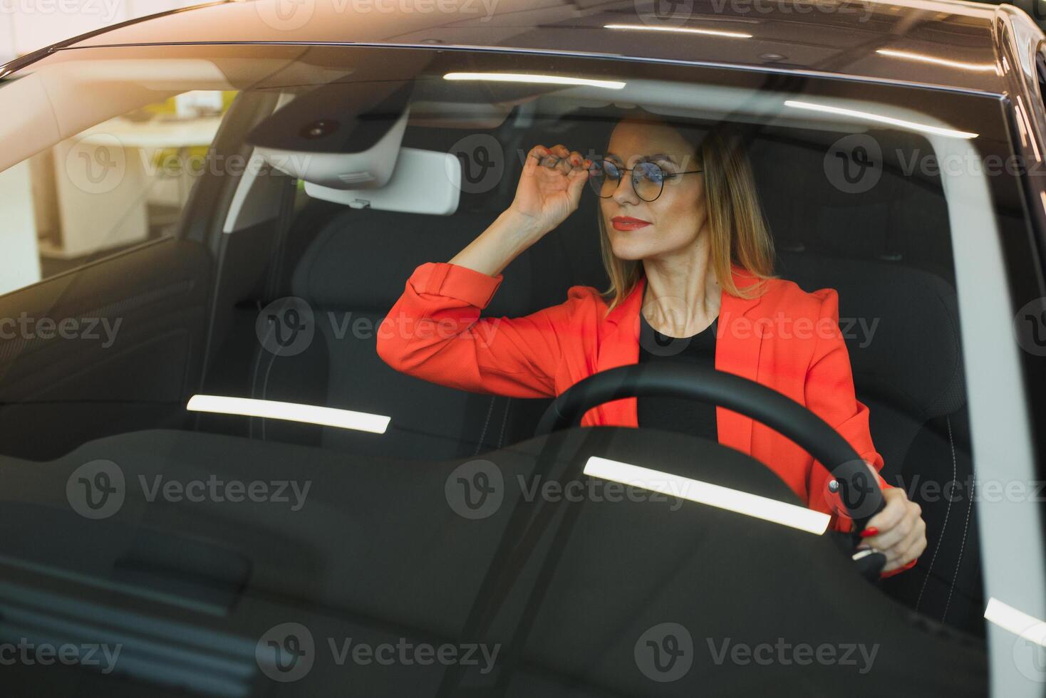 young woman looking in the rearview mirror of a car photo