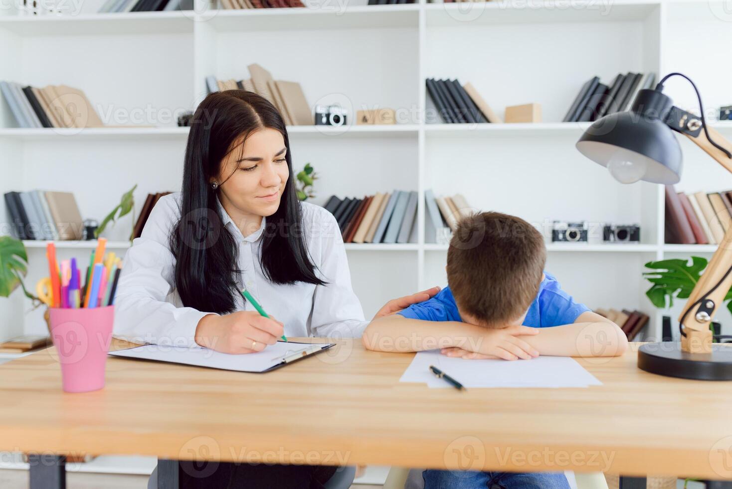 Female psychologist calming cute little boy in office photo