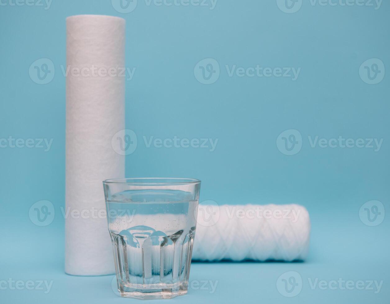 Water filters. Carbon cartridges and a glass on a blue background. Household filtration system. photo