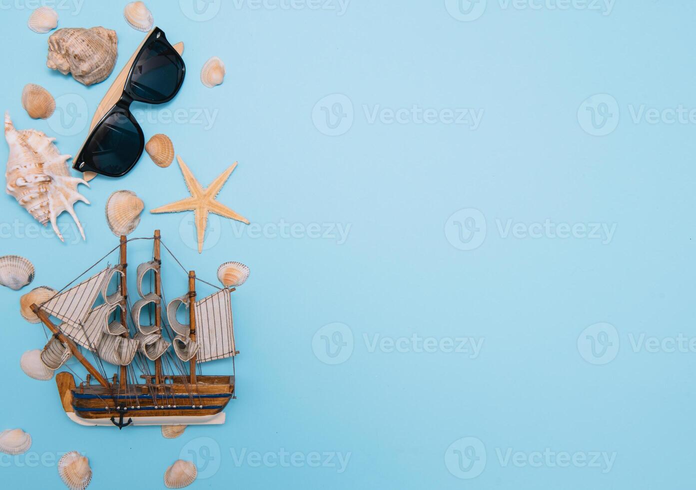 Flat lay. Top view. Frame of shells of various kinds on a blue background. Seashells and starfish and ship on a pastel background. Vacation concept. travel concept. with copy space photo