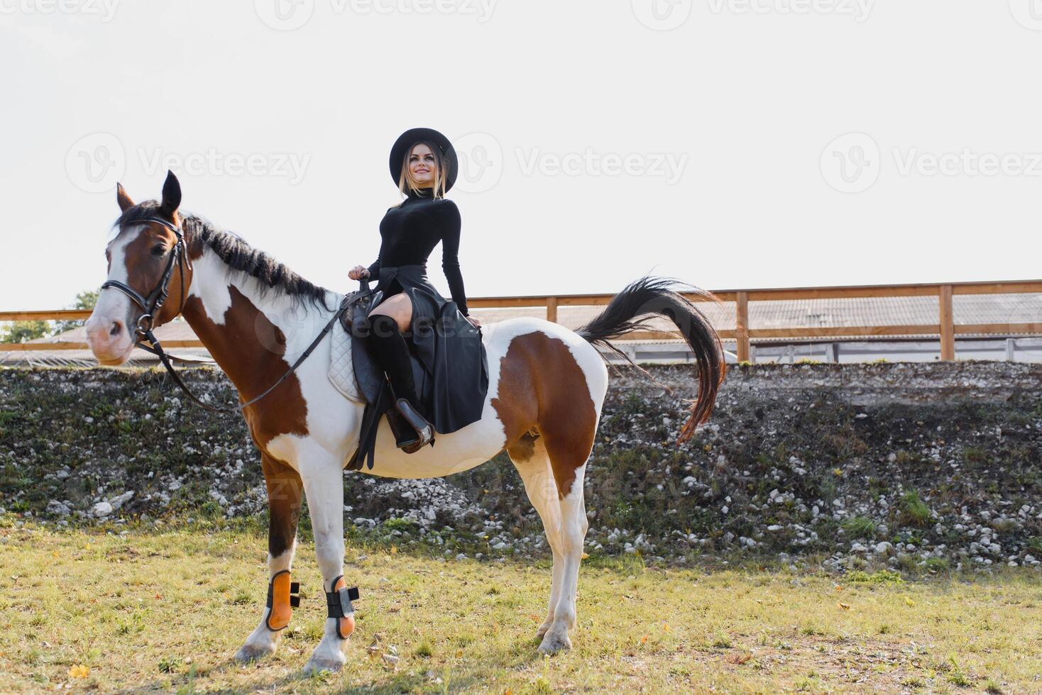 Happy fashionable young woman posing with a horse on the beach photo