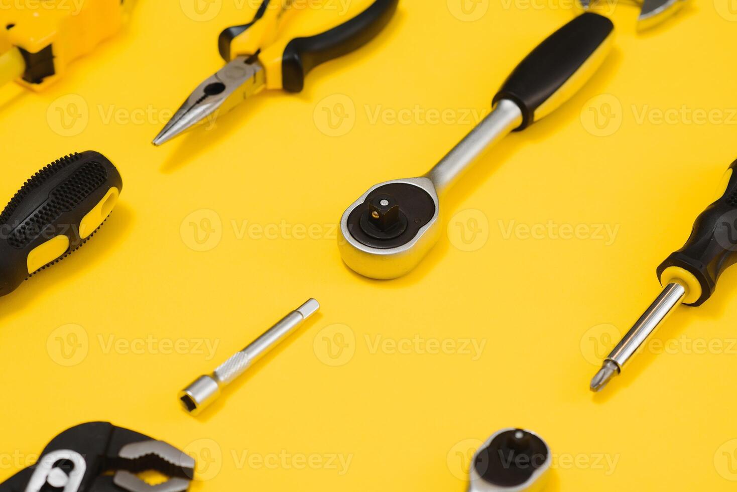 Yellow and black handy tools pilers and screwdriver isolated on yellow background. photo