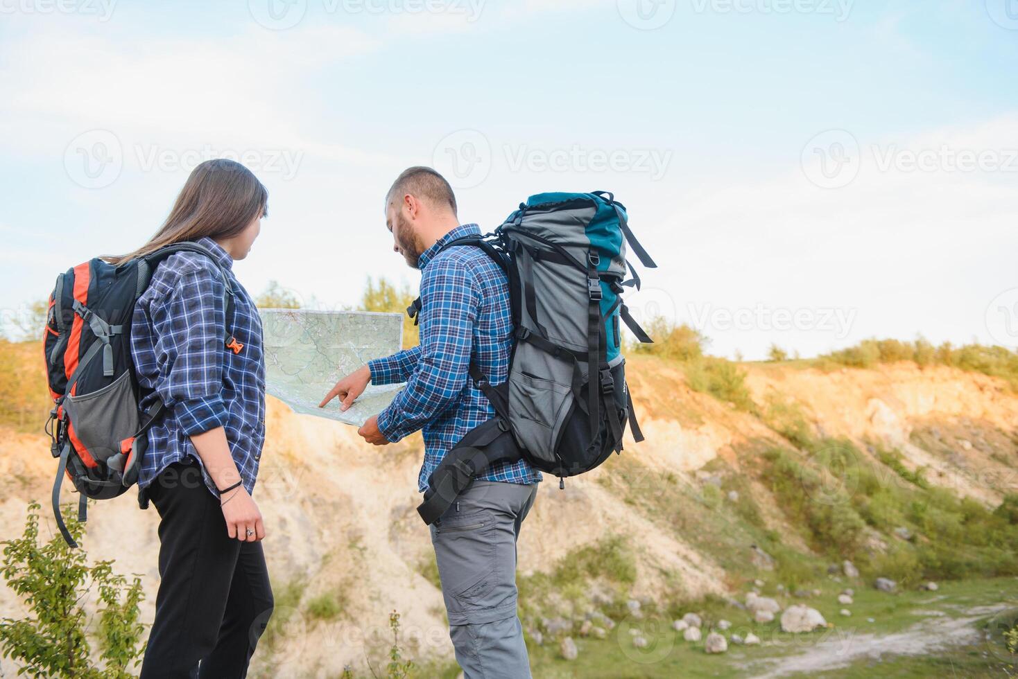 dos mochileros disfrutando paisaje naturaleza ver mientras excursionismo en nacional parque. Pareja de caminantes planificación siguiente camino a explorar participación mapa durante viajar. infografia ilustración mapa con parte superior destinos foto