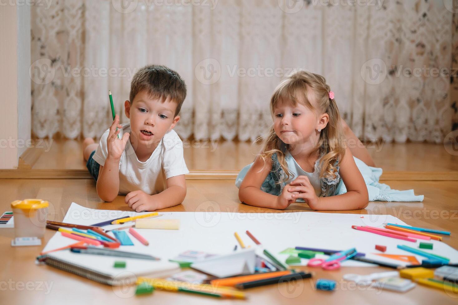 niños dibujo en piso en papel. preescolar chico y niña jugar en piso con educativo juguetes - bloques, tren, ferrocarril, avión. juguetes para preescolar y jardín de infancia. niños a hogar o guardería foto