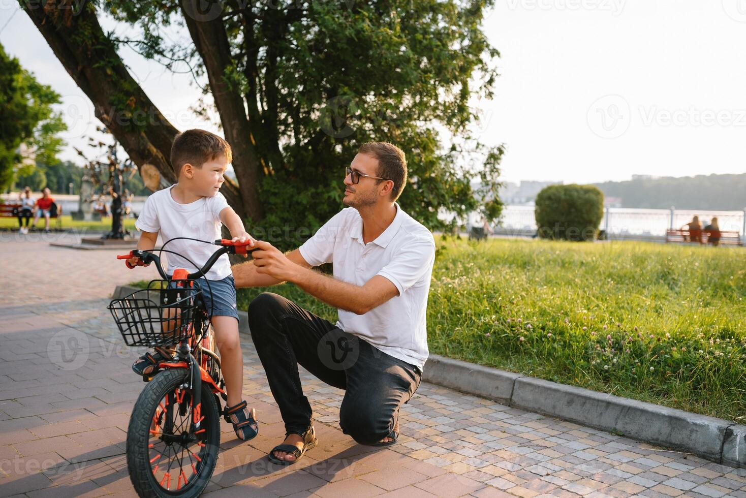 Happy father and his son having fun together at the green park, fixing bicycle together. father's day. photo