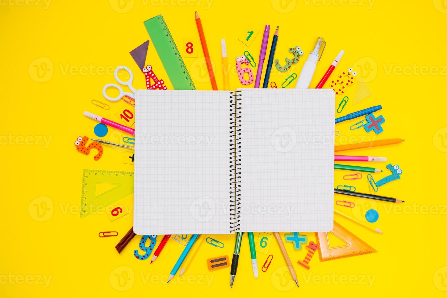 School notebook and stationery over yellow desk. Back to school abstract background. School equipment. Variety of school supplies. Flat lay photo