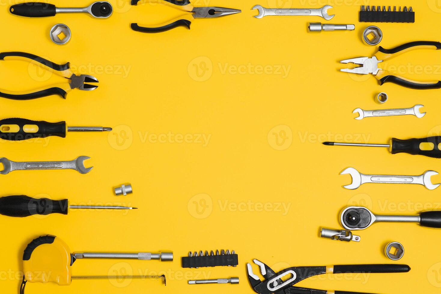 Yellow and black handy tools pilers and screwdriver isolated on yellow background. photo