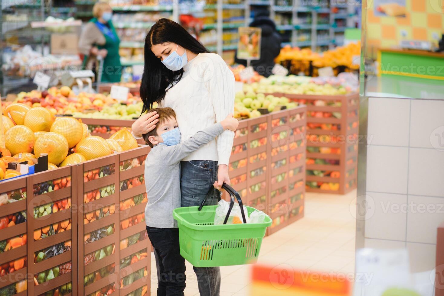 joven mujer y su niño vistiendo protector cara mascaras tienda un comida a un supermercado durante el coronavirus epidemia o gripe brote. foto