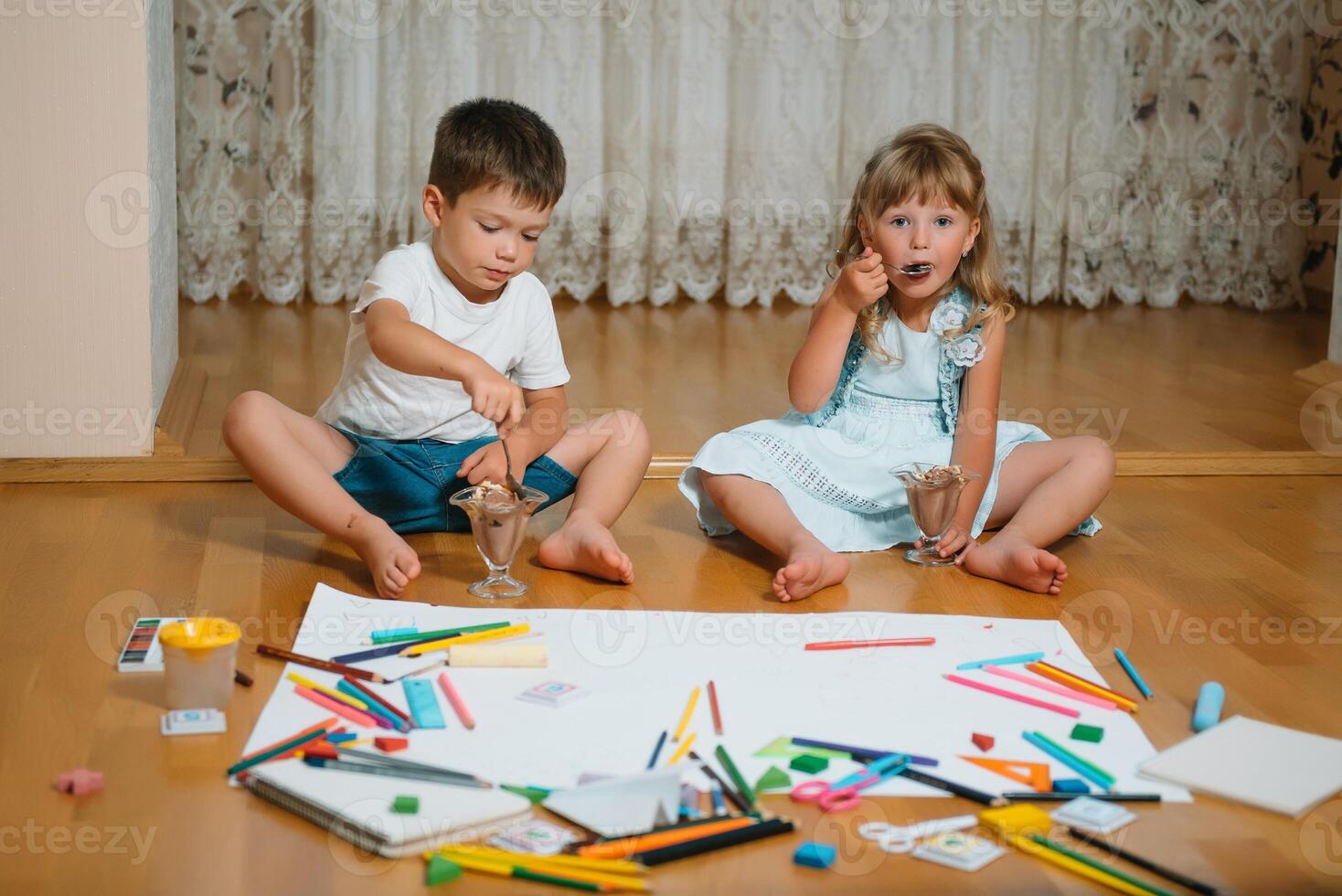 Kids drawing on floor on paper. Preschool boy and girl play on floor with educational toys - blocks, train, railroad, plane. Toys for preschool and kindergarten. Children at home or daycare. photo