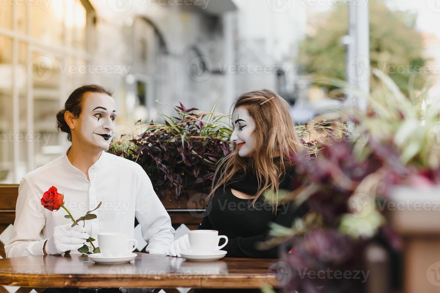 mime guy and girl in cafe drinking coffee. Mime in front of Paris cafe acting like drinking tea or coffee. photo