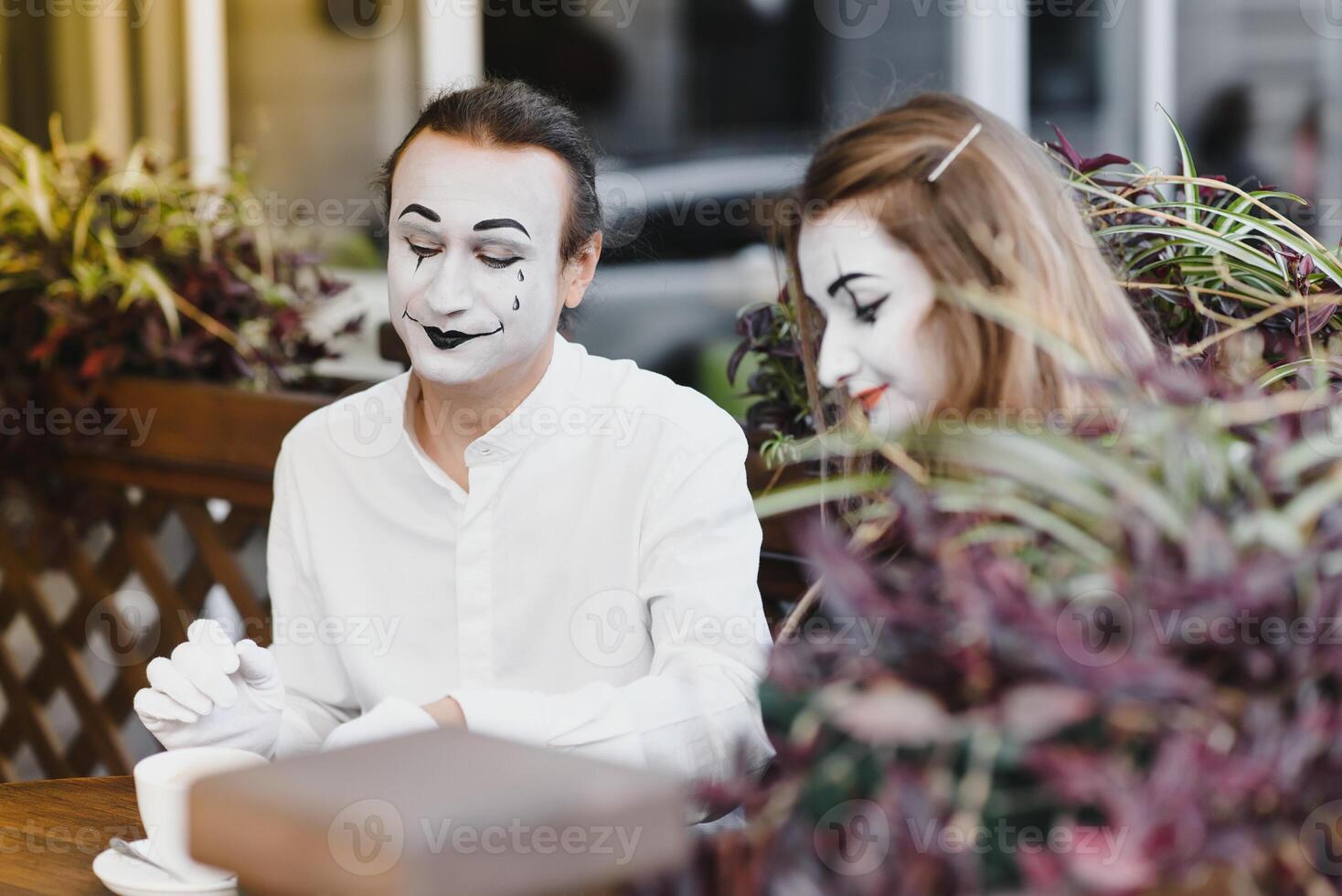 mime guy and girl in cafe drinking coffee. Mime in front of Paris cafe acting like drinking tea or coffee. photo