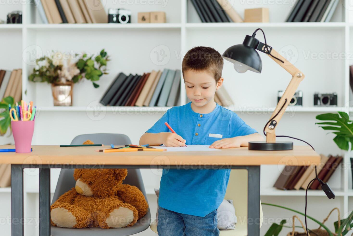 education, childhood, people, homework and school concept - smiling student boy with book writing to notebook at home photo