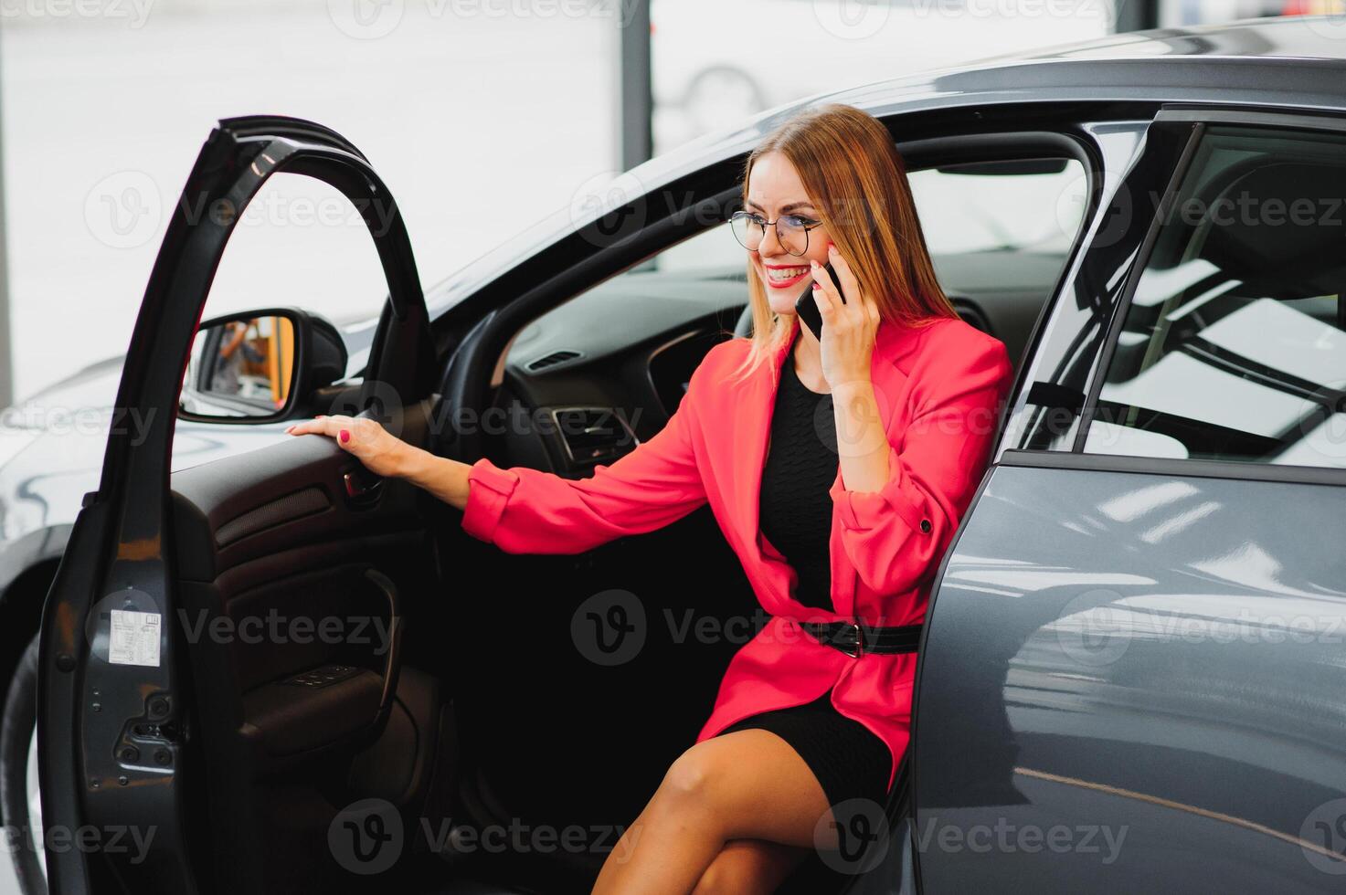 attractive businesswoman sitting in the car, talking on the phone and smiling photo