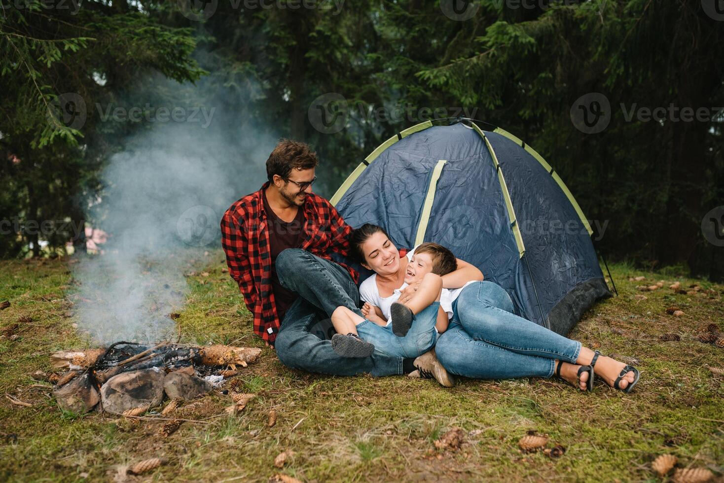 Family near the fire in the forest. Parent with child on a tent background. National Park. Hike with children. Active summer holidays photo