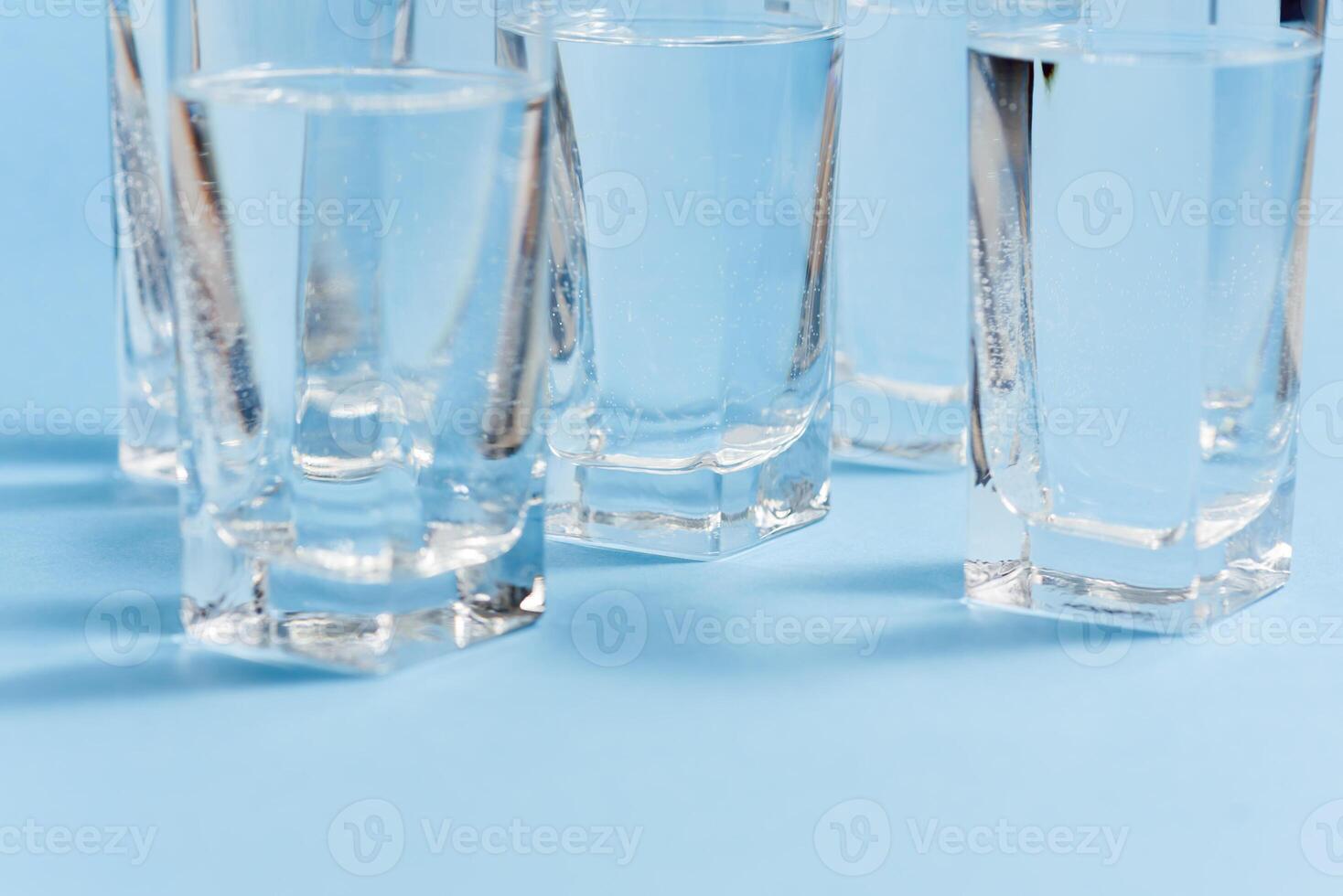 Glasses of water on blue. Close up. Copy space. Water balance for healthy and detox. photo