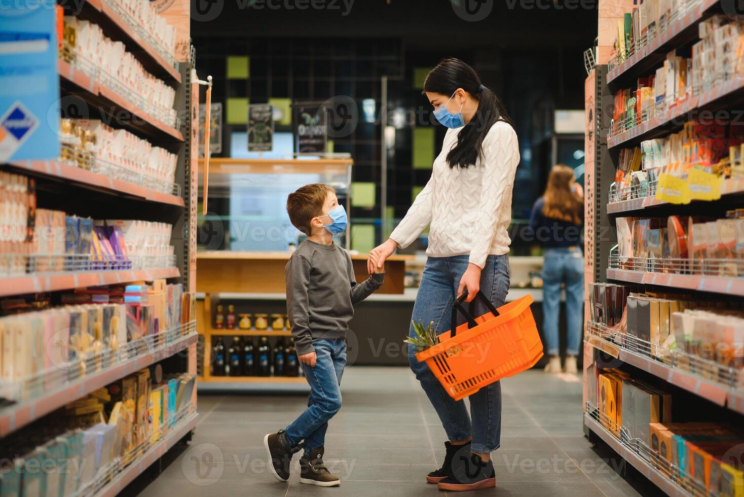 joven mujer y su pequeño hijo vistiendo protector cara máscara tienda un comida a un supermercado durante el coronavirus epidemia o gripe brote. foto