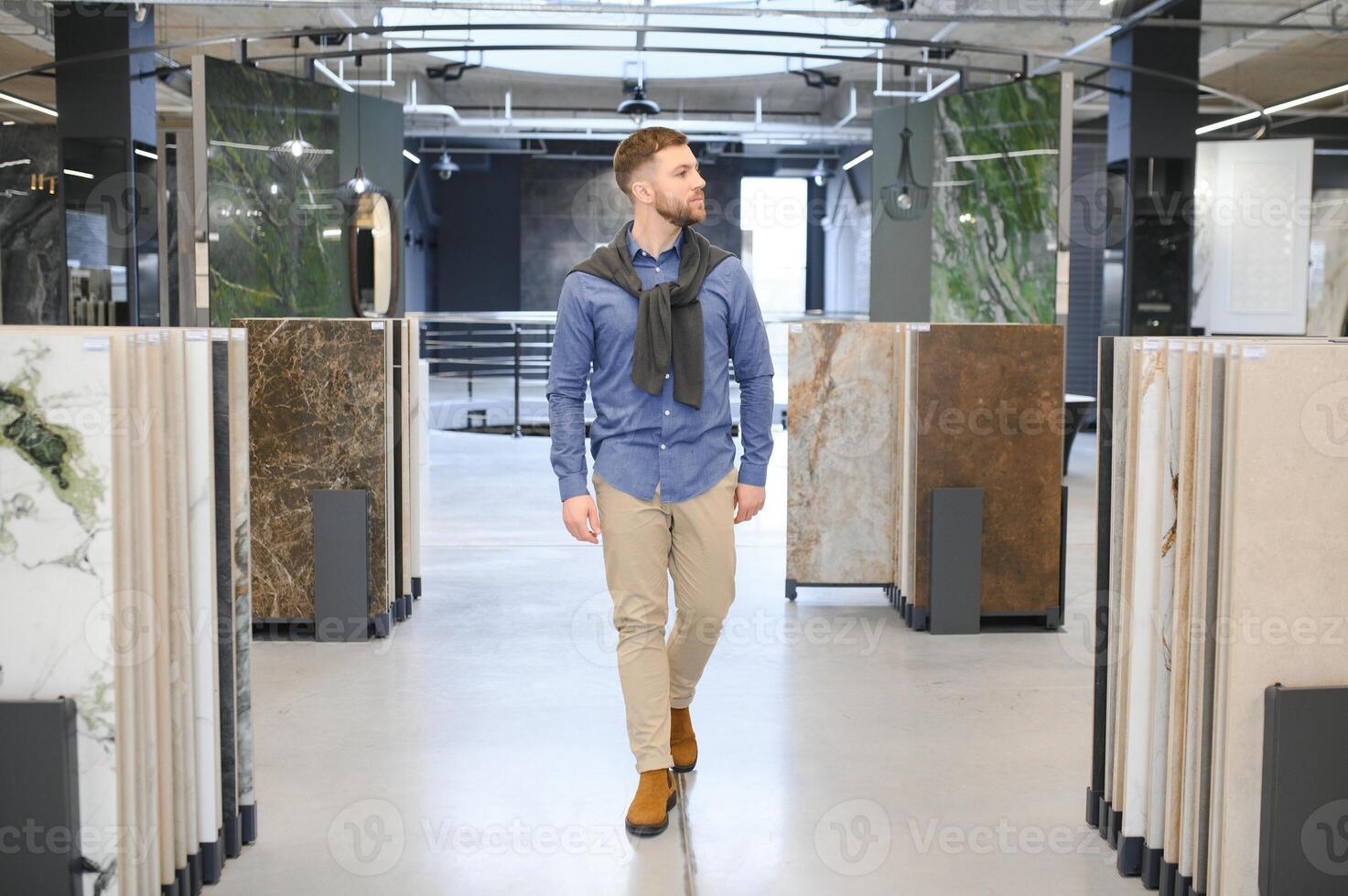 Young man choosing tiles at building market photo